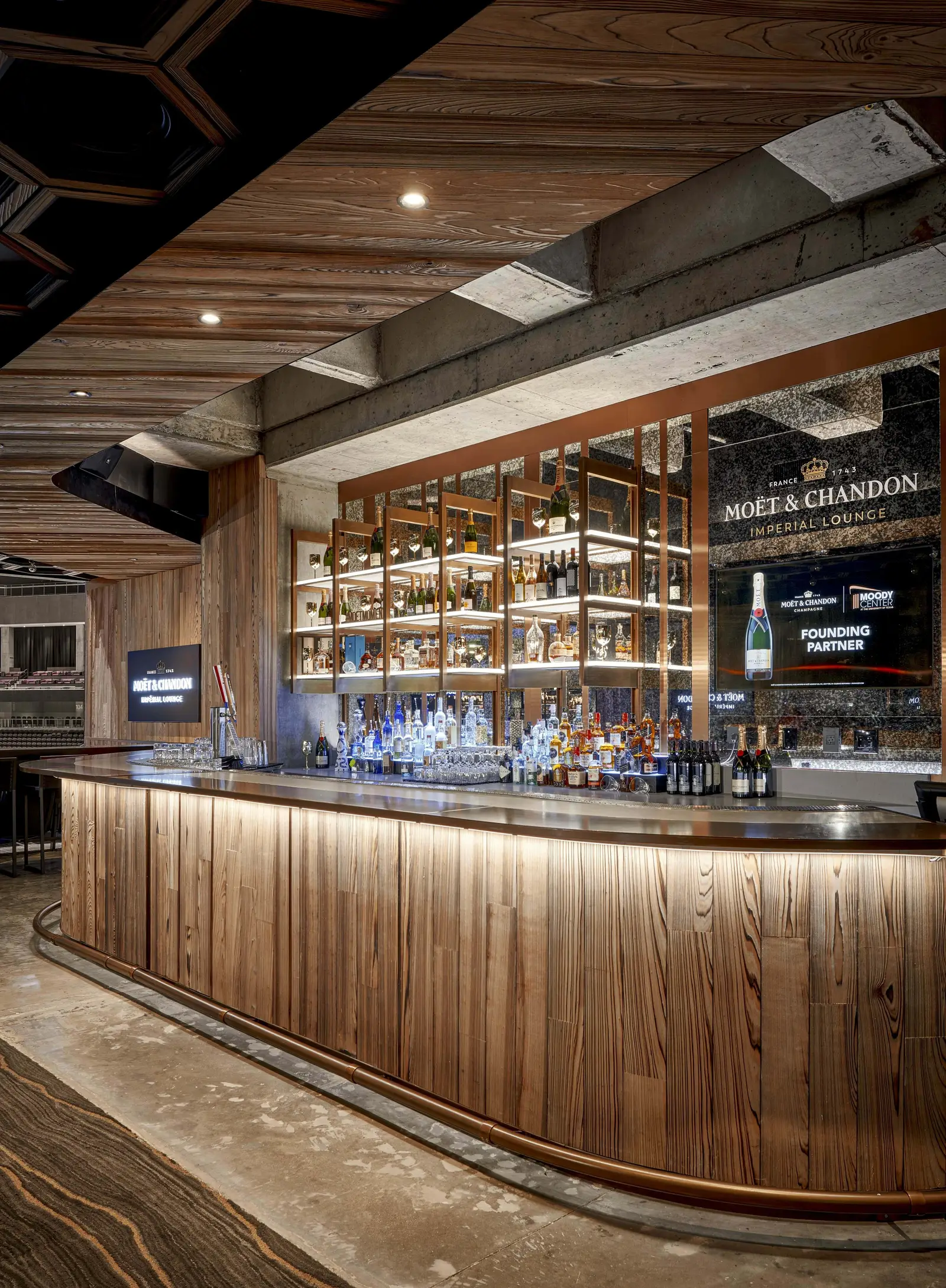 Moody Center bar with a curved wood-front counter and lit back-bar shelves