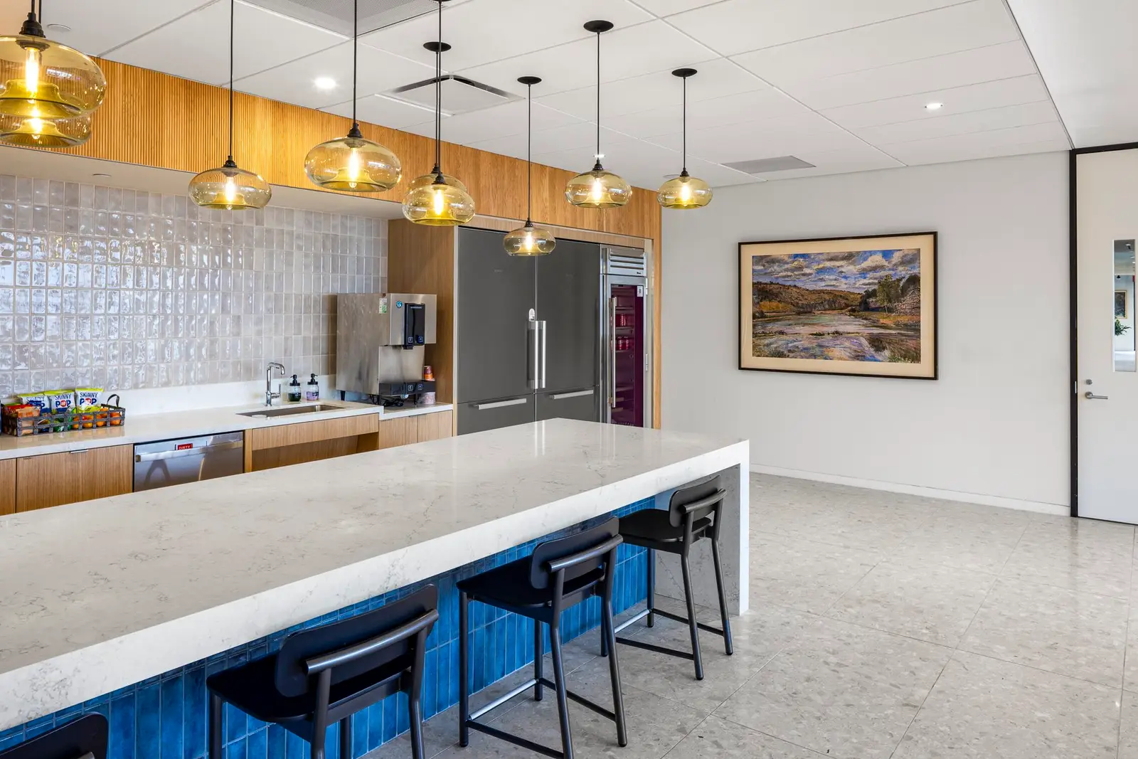 Norton Rose Fulbright pantry with a white stone counter, blue tile base and glass pendant lights