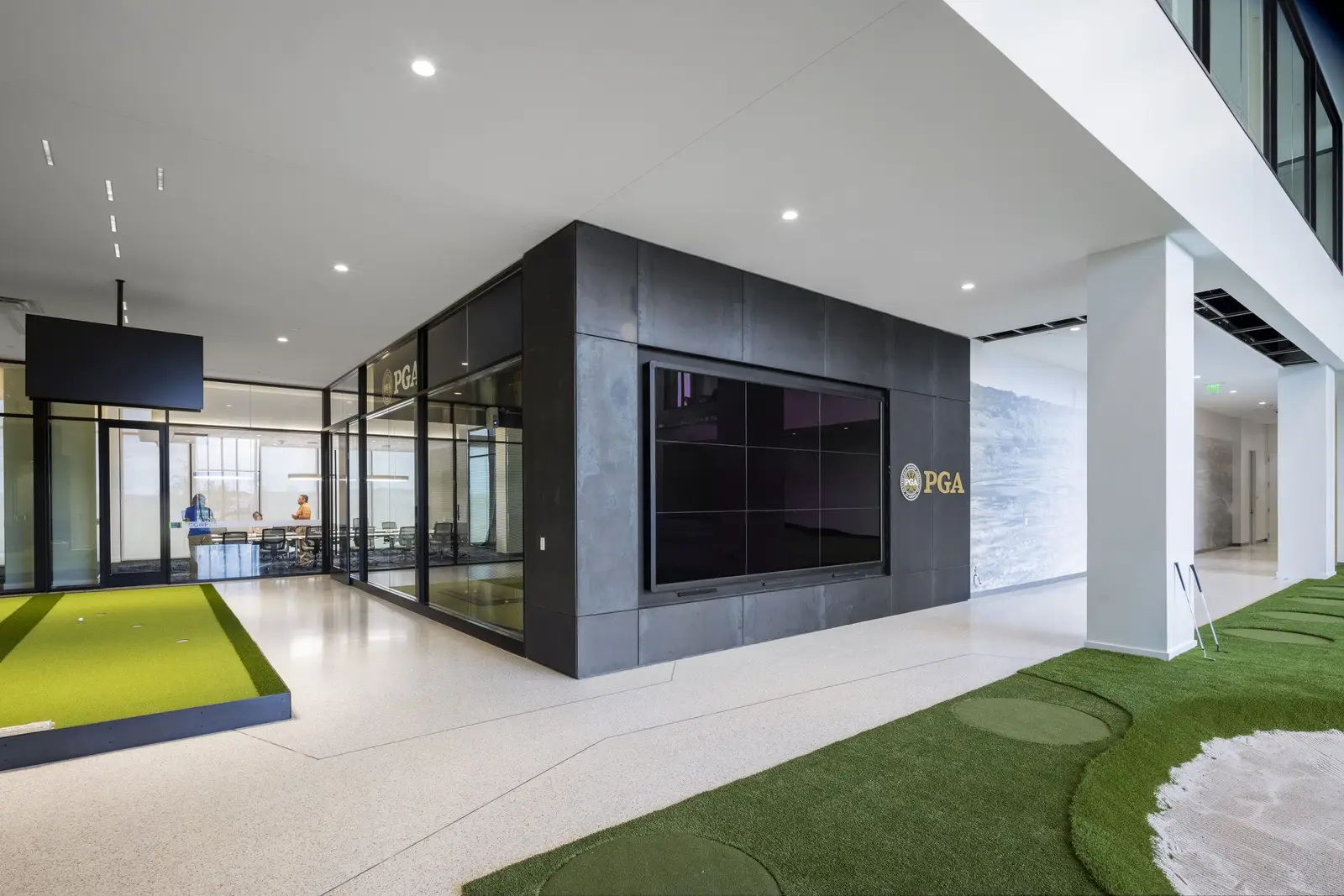 PGA of America dark metal-clad volume with a screen beside a putting green
