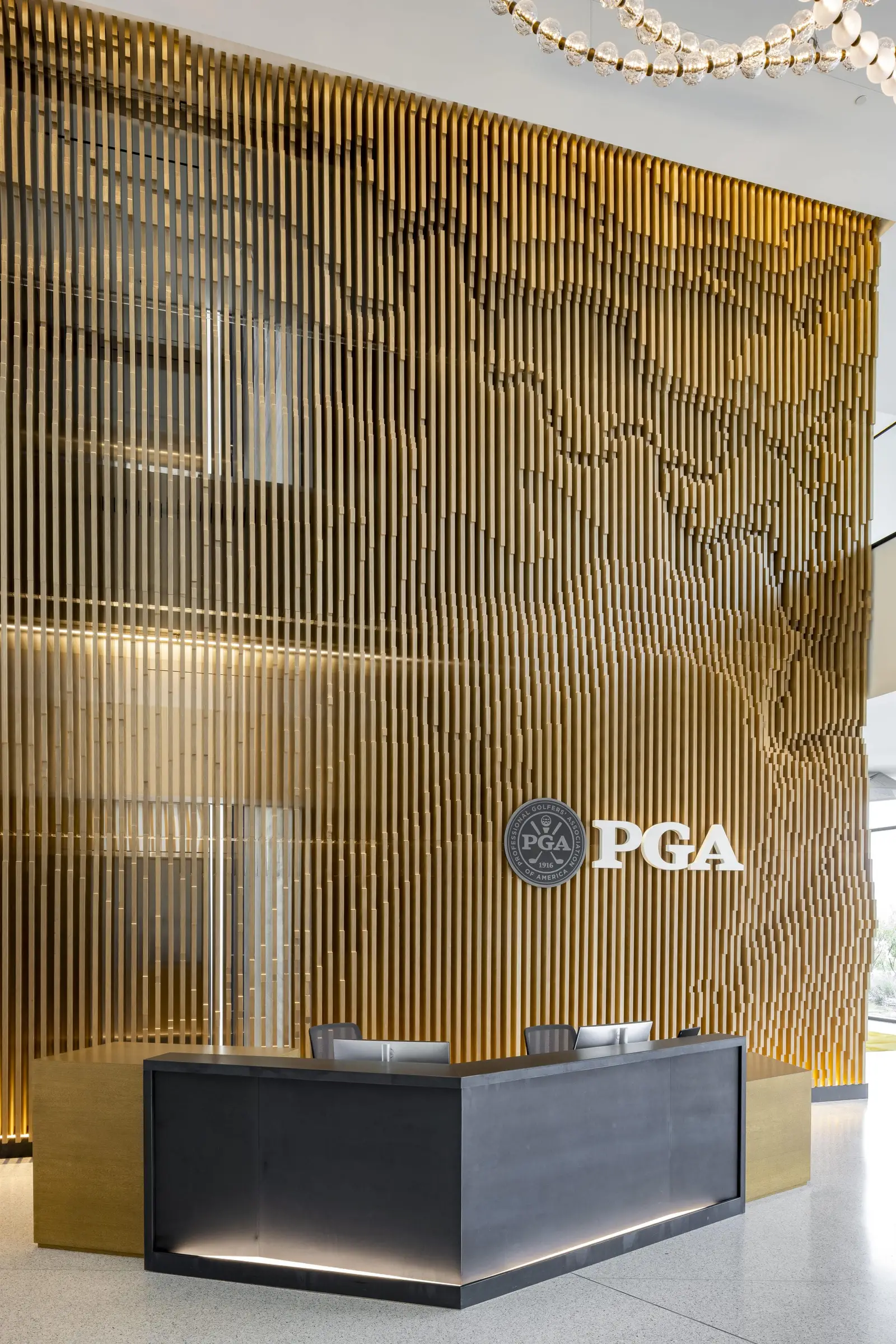 PGA of America tall slatted wood feature wall with a PGA logo above a reception desk