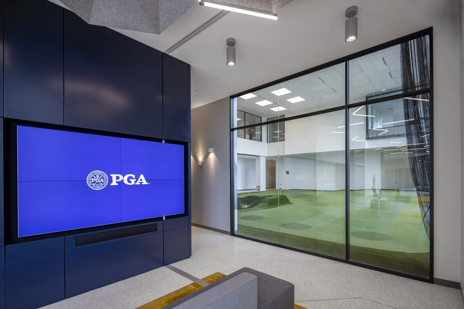 PGA of America blue video wall with the PGA logo beside an indoor putting green