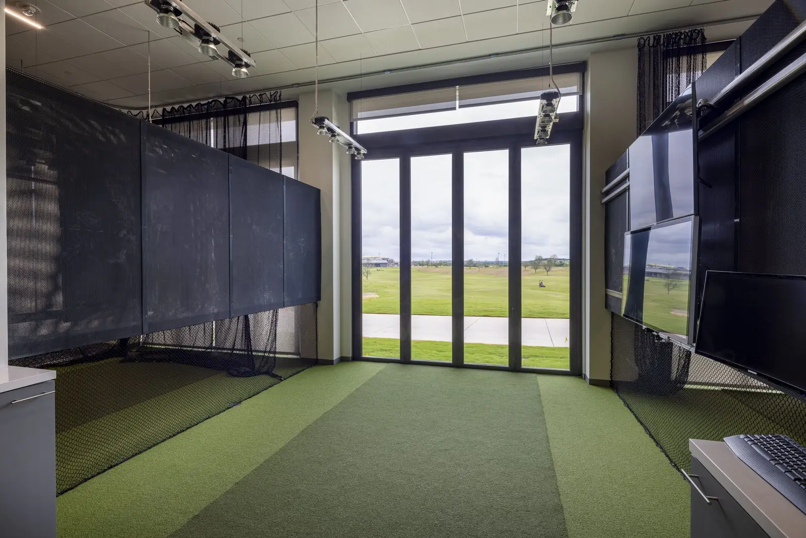 PGA of America indoor golf area with turf and a dark metal-clad wall