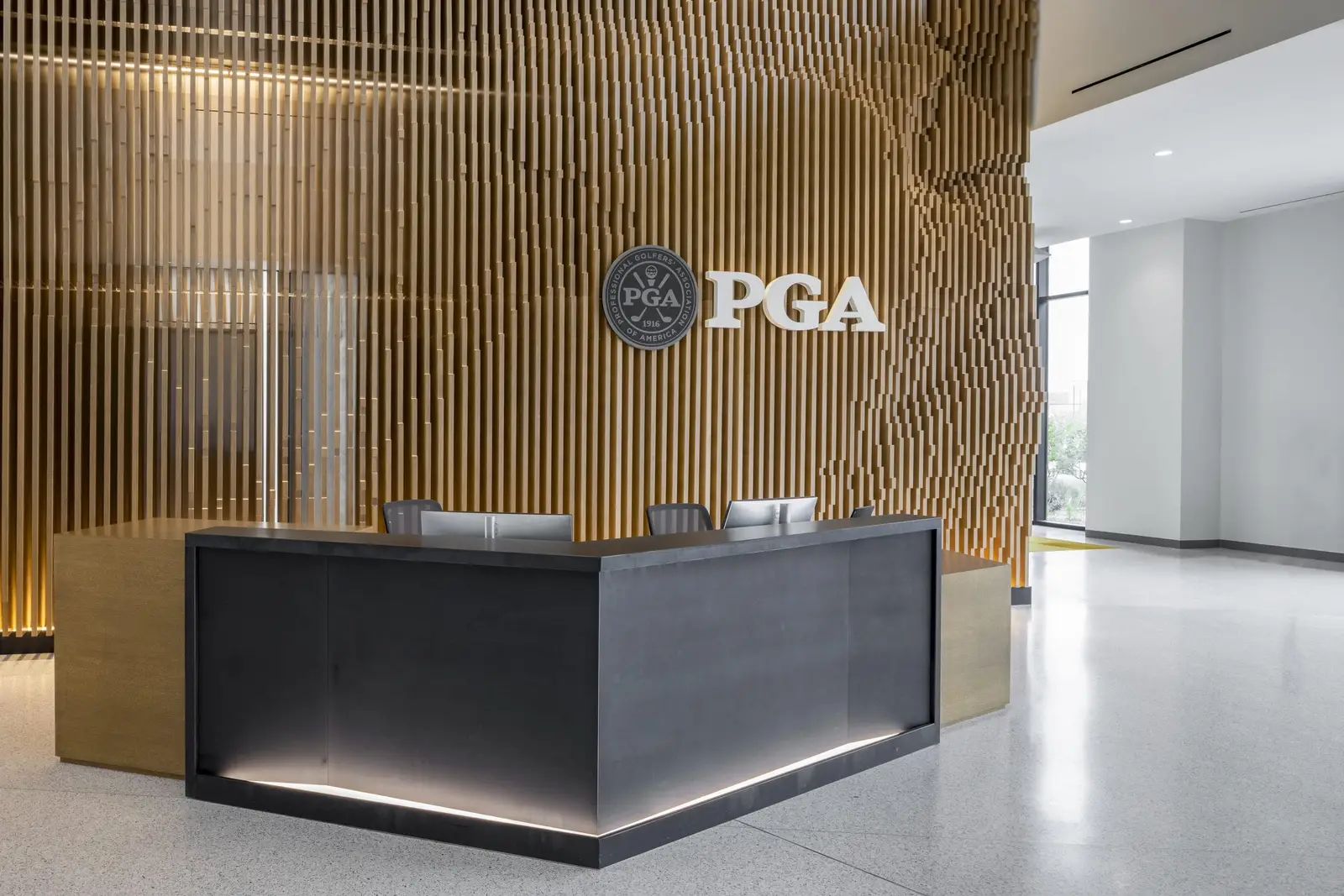 PGA of America reception desk and slatted wood wall with the PGA logo