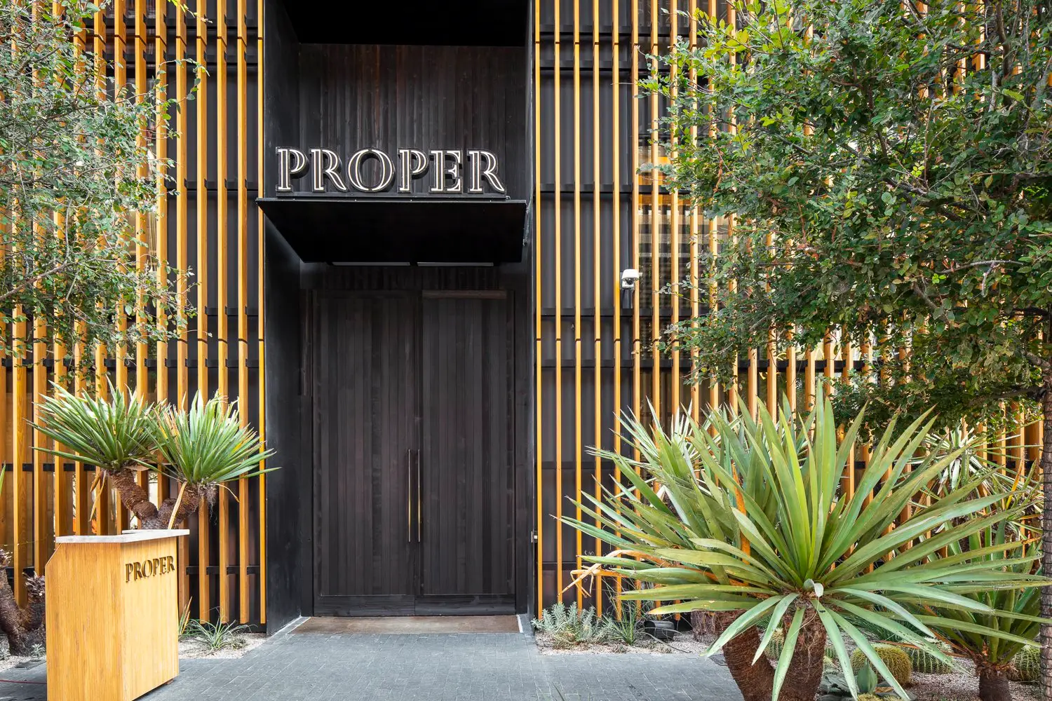 Austin Proper Hotel hotel entrance with vertical wood slats, a dark door and the PROPER sign