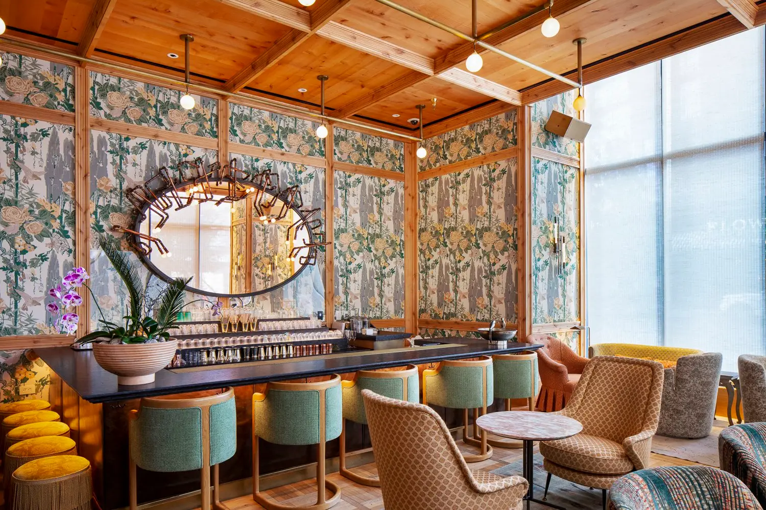 Austin Proper Hotel bar with patterned wallpaper, a wood ceiling and teal stools