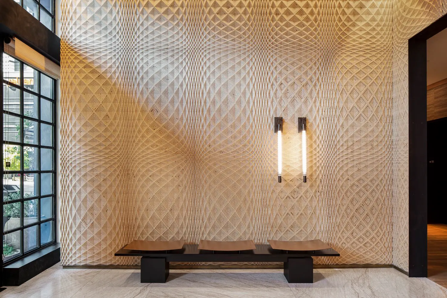 Austin Proper Hotel entry with a milled diamond-lattice wood wall, a bench and two light fixtures