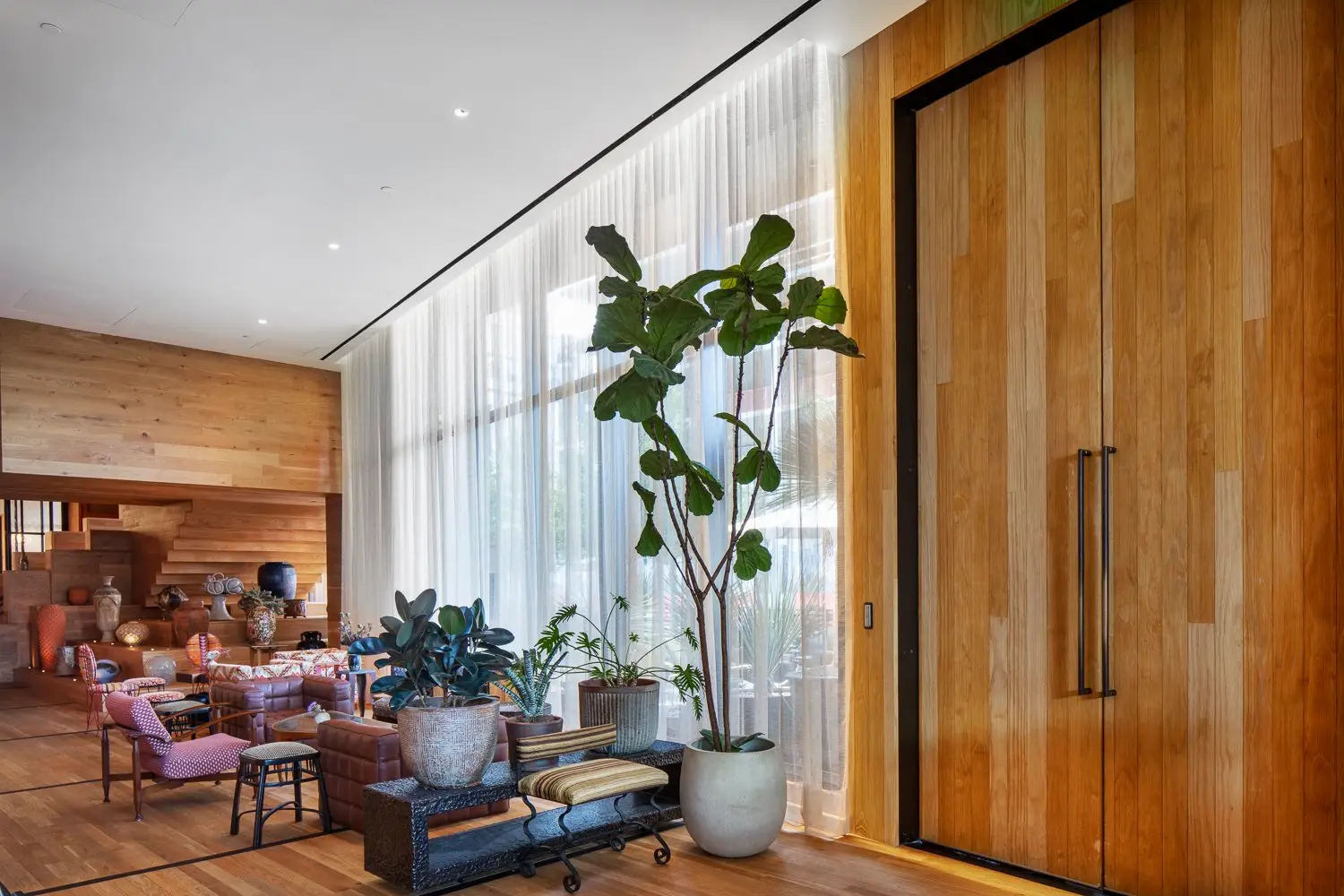 Austin Proper Hotel lobby lounge with a tall wood door and sheer curtains