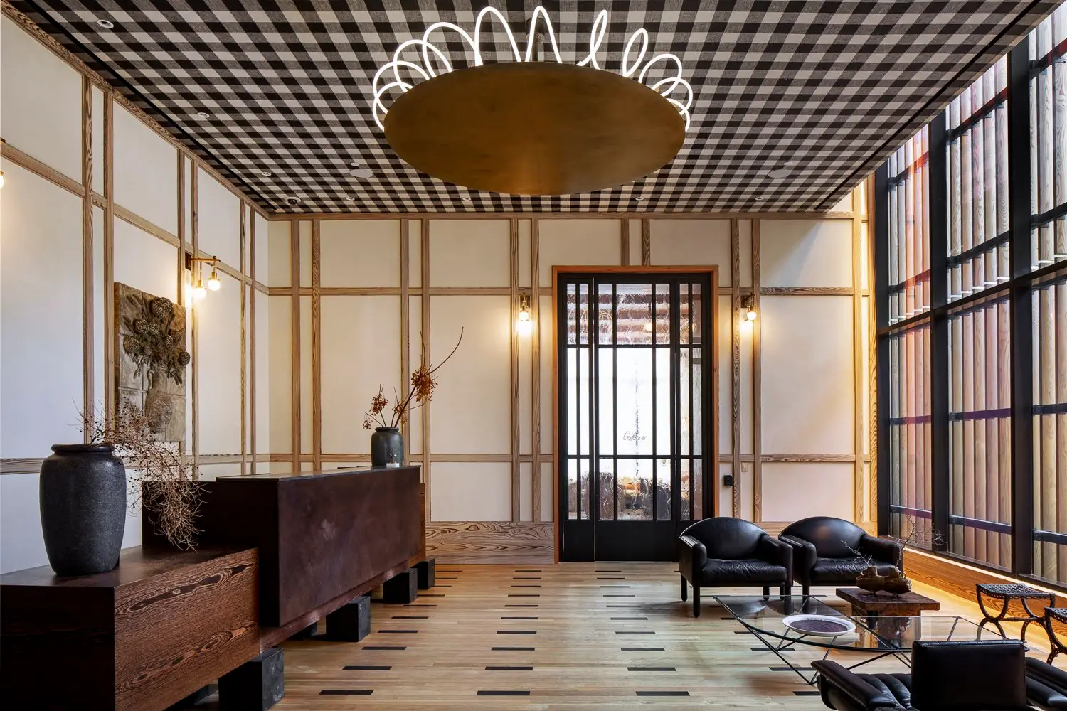 Austin Proper Hotel lobby with a checkered ceiling, black-framed glass doors and a wood console