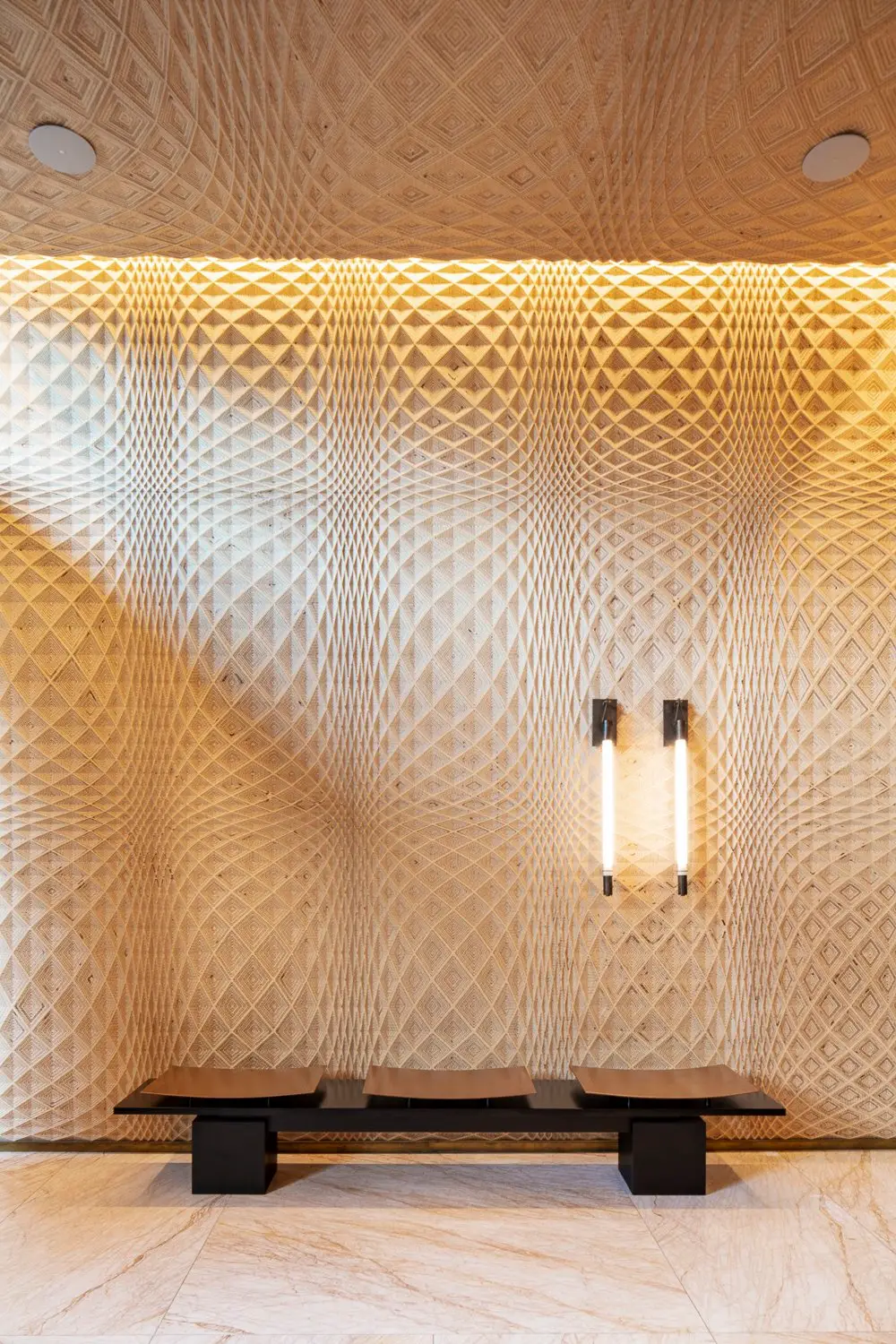 Austin Proper Hotel diamond-lattice wood wall with a bench and two light fixtures, close view