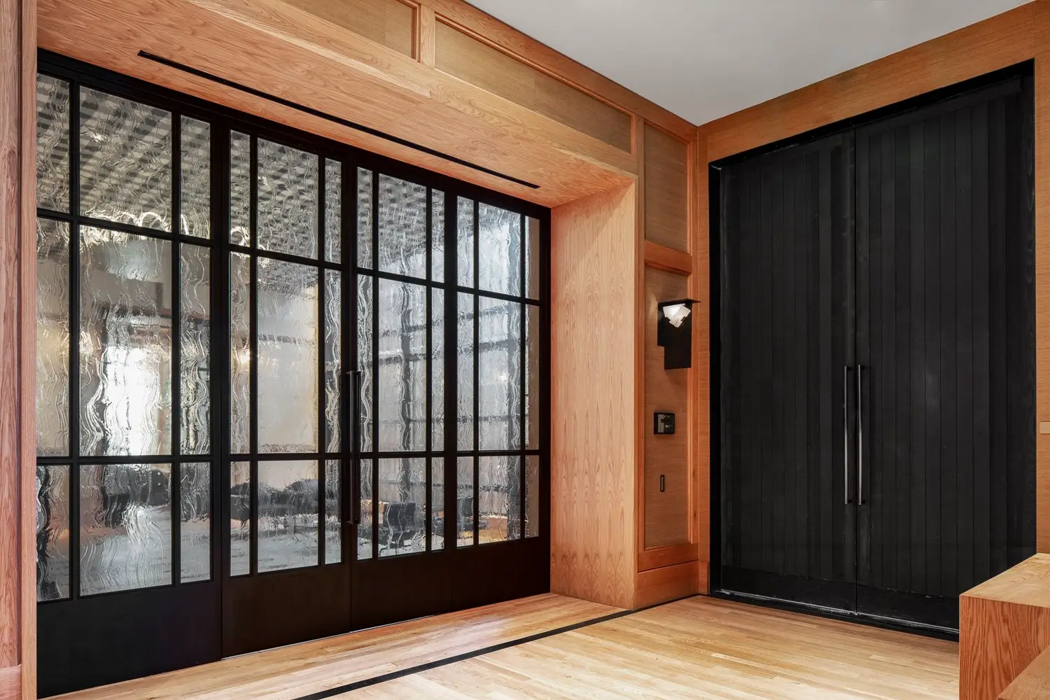 Austin Proper Hotel black-framed glass wall beside a large dark double door in a wood-lined opening