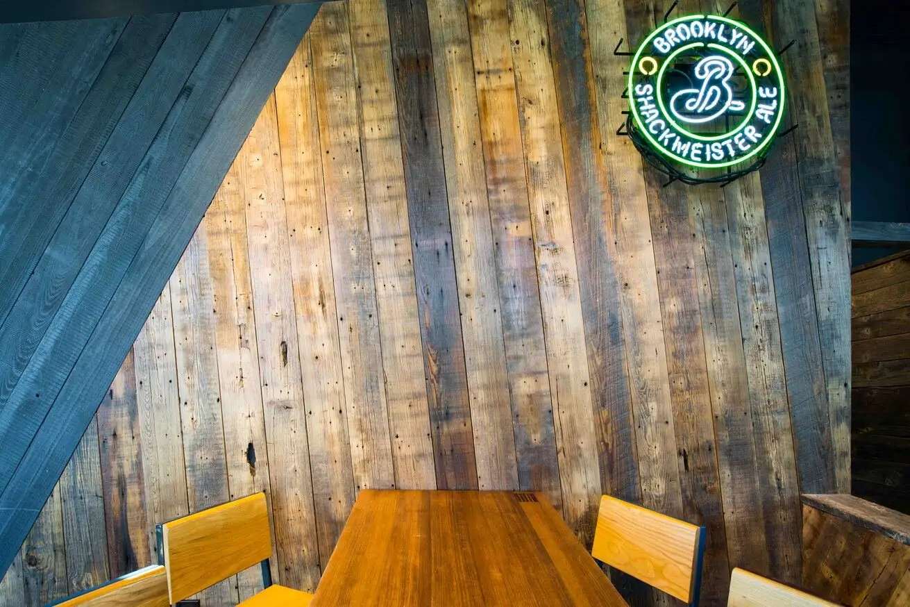 Shake Shack S. Lamar reclaimed wood wall with a neon sign above a table