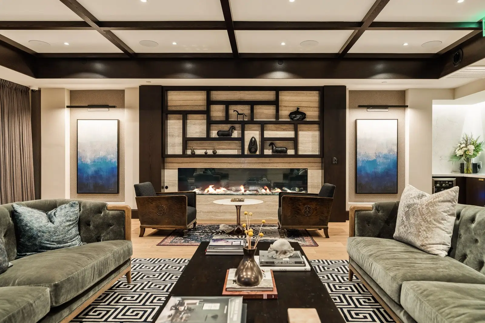 Sixth and Guadalupe lounge with green sofas, a coffered ceiling and a built-in shelving wall