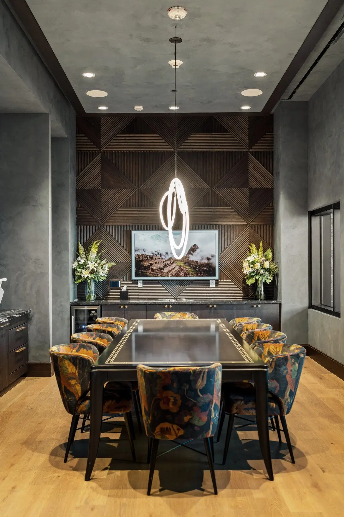 Sixth and Guadalupe conference room with a long dark table, patterned chairs and a wood-paneled feature wall