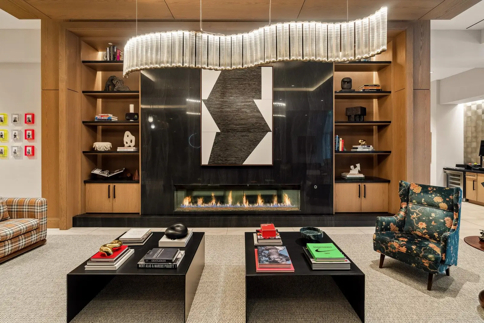 Sixth and Guadalupe lounge with a wood-framed fireplace wall, built-in shelves and a wavy light fixture