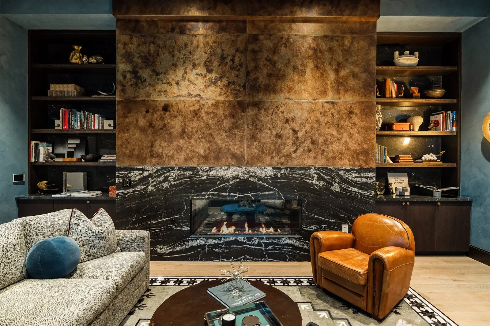 Sixth and Guadalupe lounge with a stone fireplace, copper-tone wall panel and built-in bookshelves