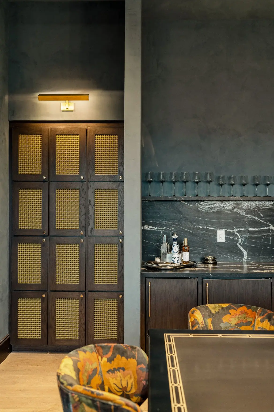 Sixth and Guadalupe bar nook with a mesh-front cabinet door and dark stone backsplash