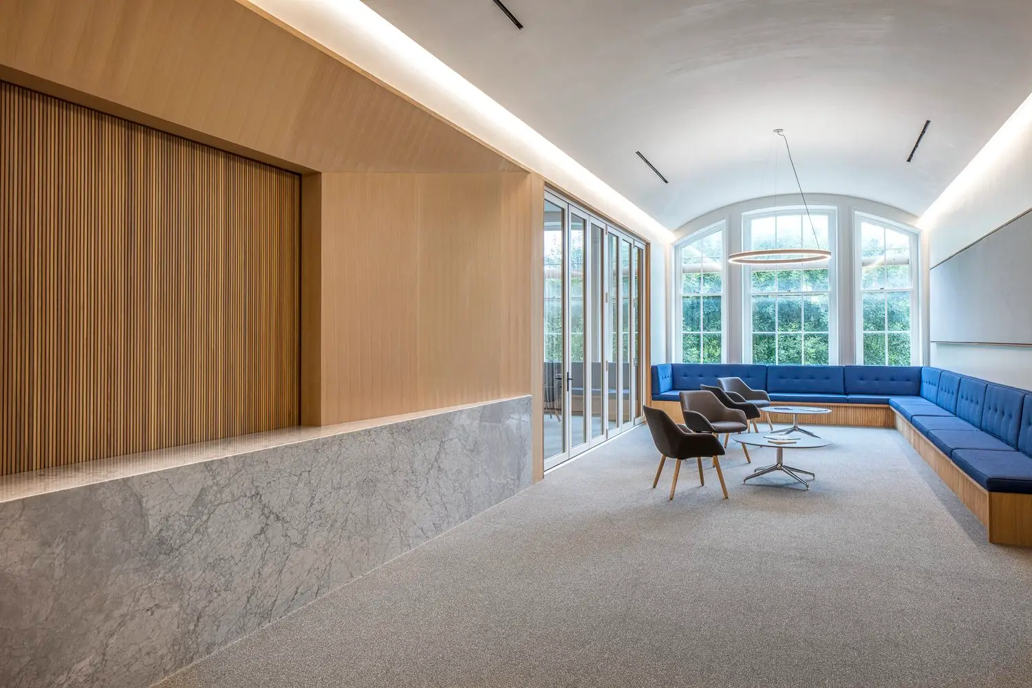 St. Edward's University lounge with a stone-faced wall, a wood slat panel and a blue banquette
