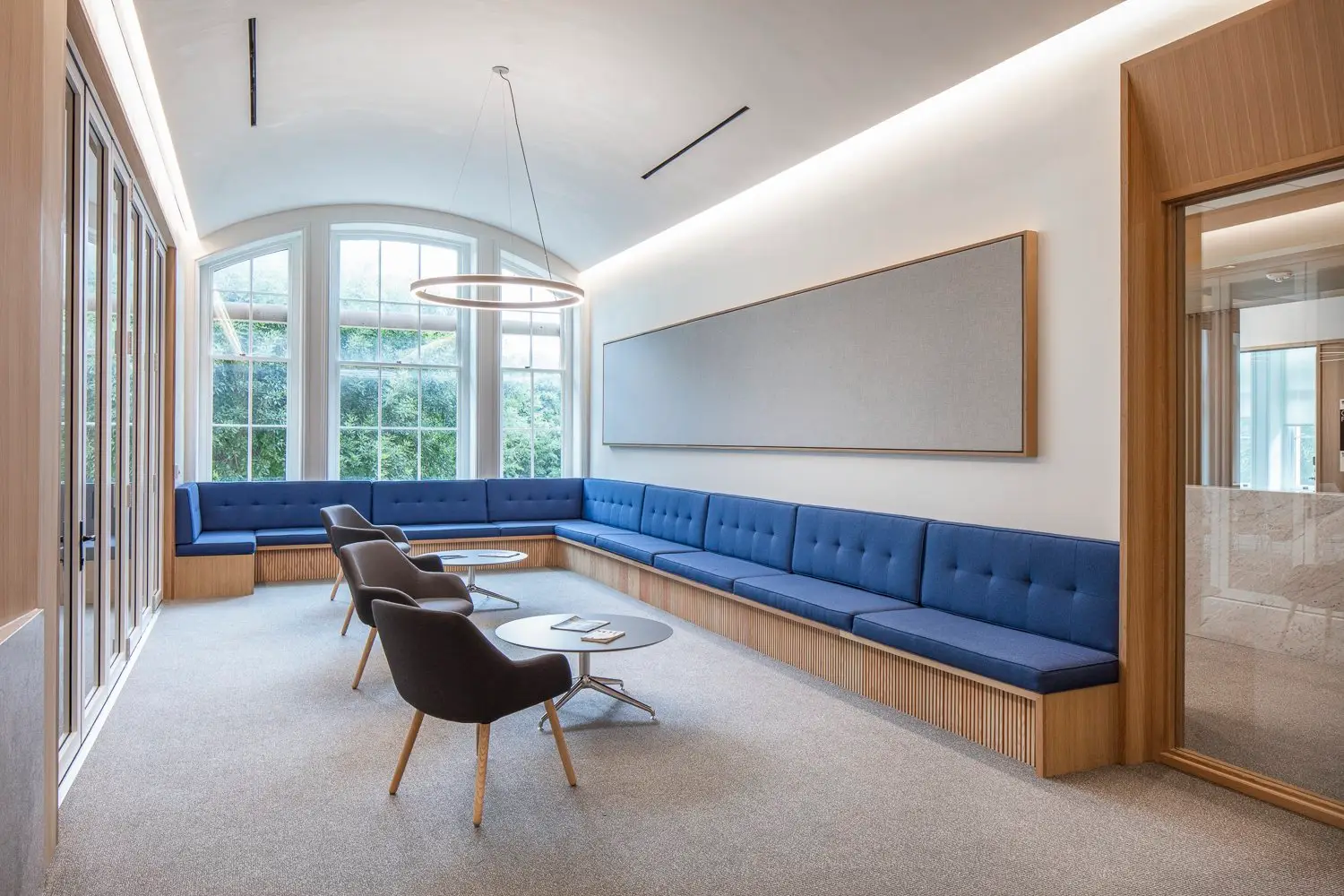 St. Edward's University lounge with a long blue banquette, arched windows and a wood-framed opening