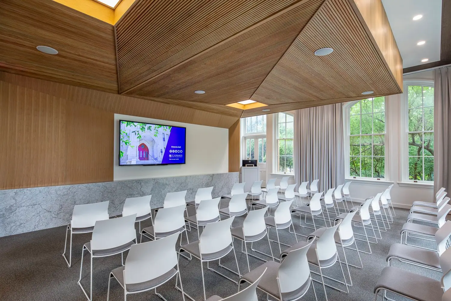 St. Edward's University presentation room with a faceted wood ceiling and white chairs