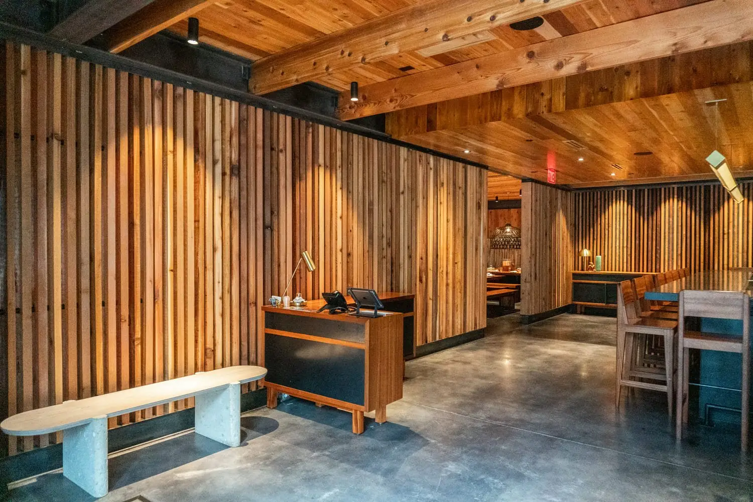 Sway Domain host stand and wood slat wall with a bench at the entry