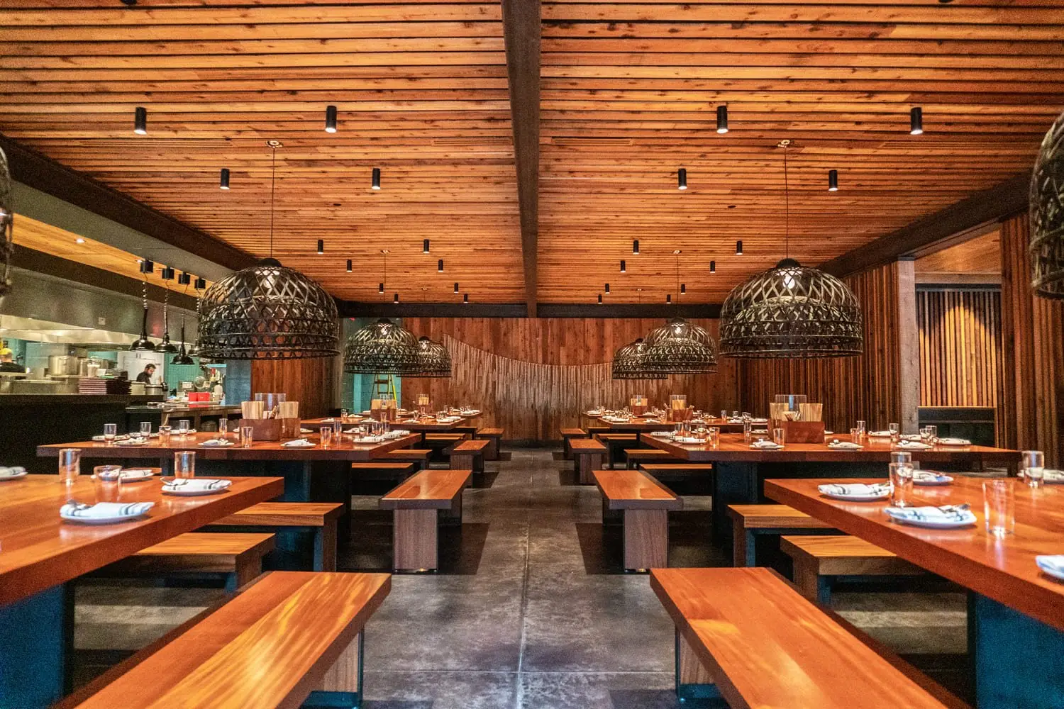 Sway Domain restaurant dining room with wood tables and an open kitchen beyond