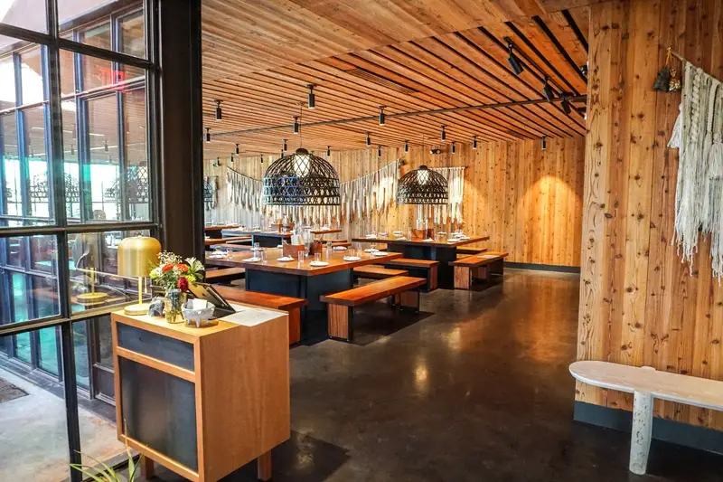 Sway Bee Caves restaurant with a wood slat ceiling, wood-clad columns and communal tables