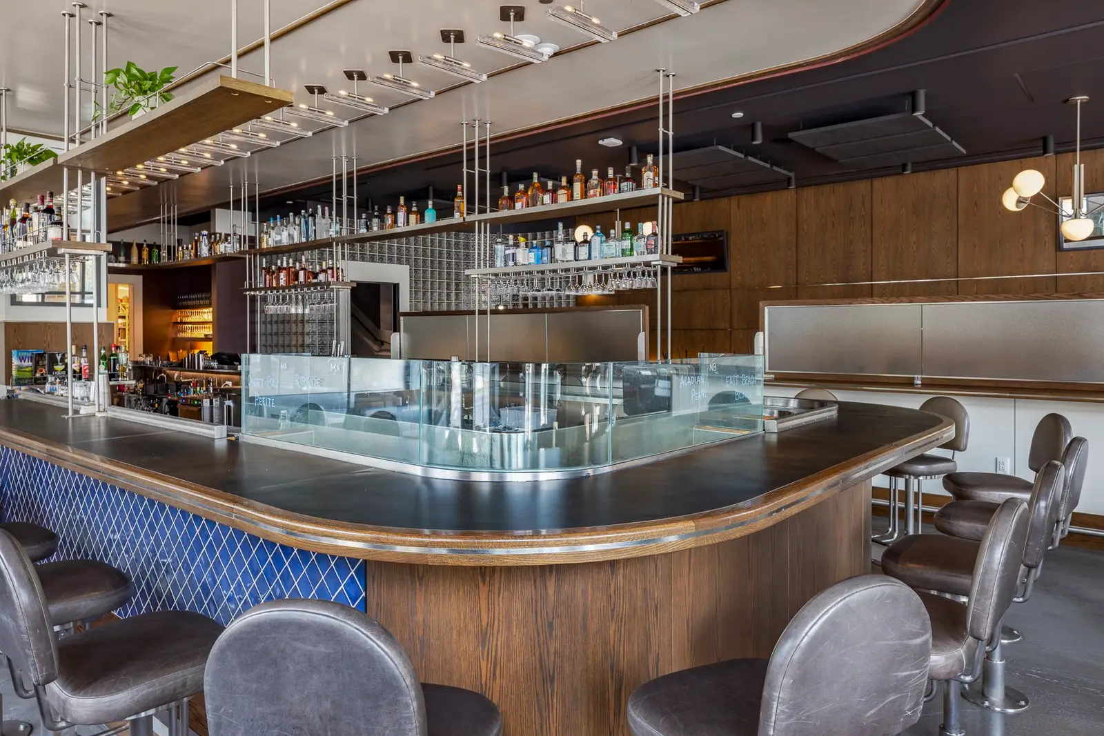 Thompson Hotel bar with a curved wood-front counter and blue tile base