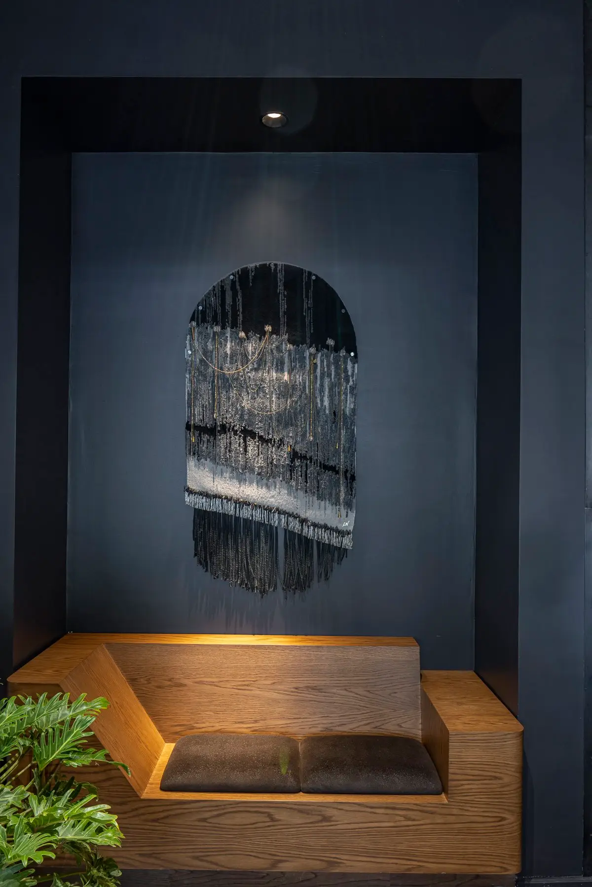Thompson Hotel wall niche with a wood bench and a dark arched artwork
