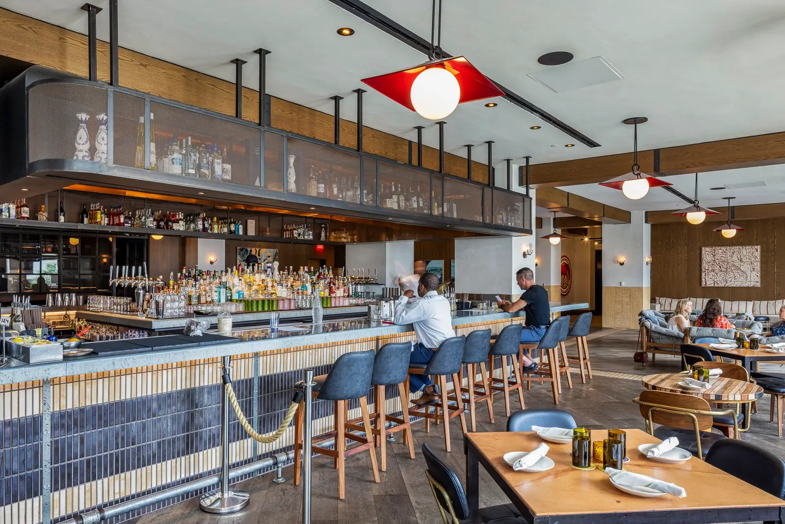 Thompson Hotel bar with a tiled front, high stools and a hanging glass rack