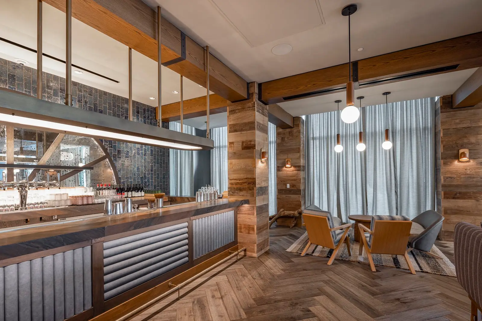 Thompson Hotel dining area beside a bar with wood beams and a herringbone floor