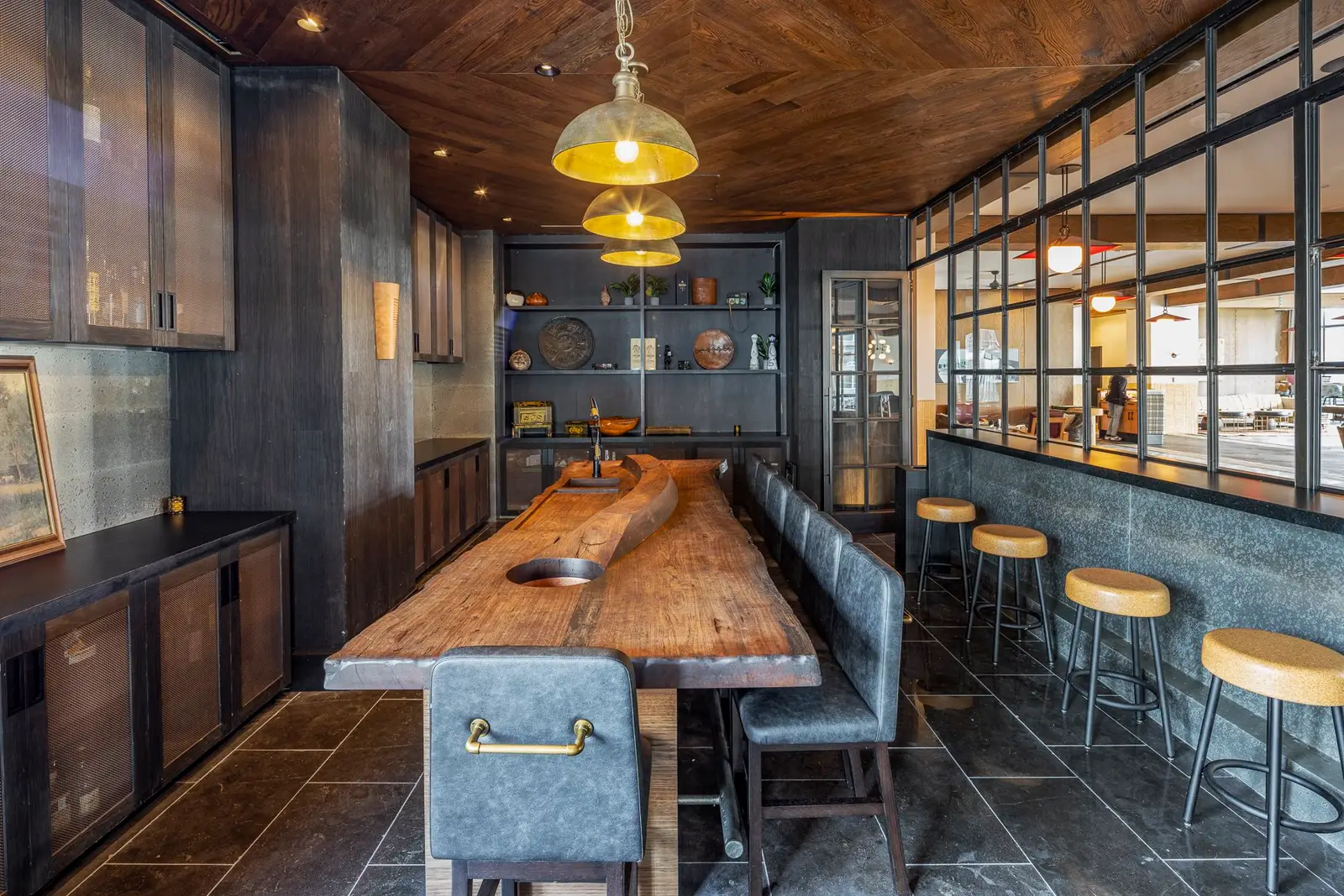 Thompson Hotel private dining table with a live-edge wood top beside a metal-framed glass wall