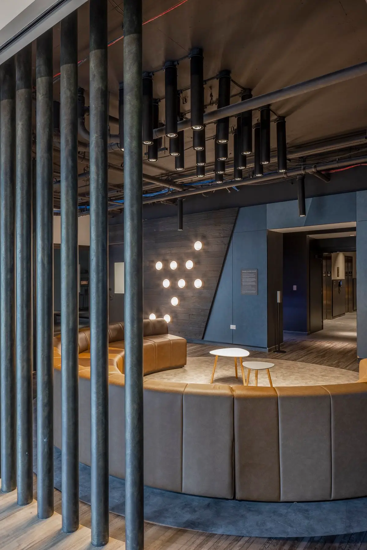 Thompson Hotel curved banquette lounge seen through vertical metal pipes