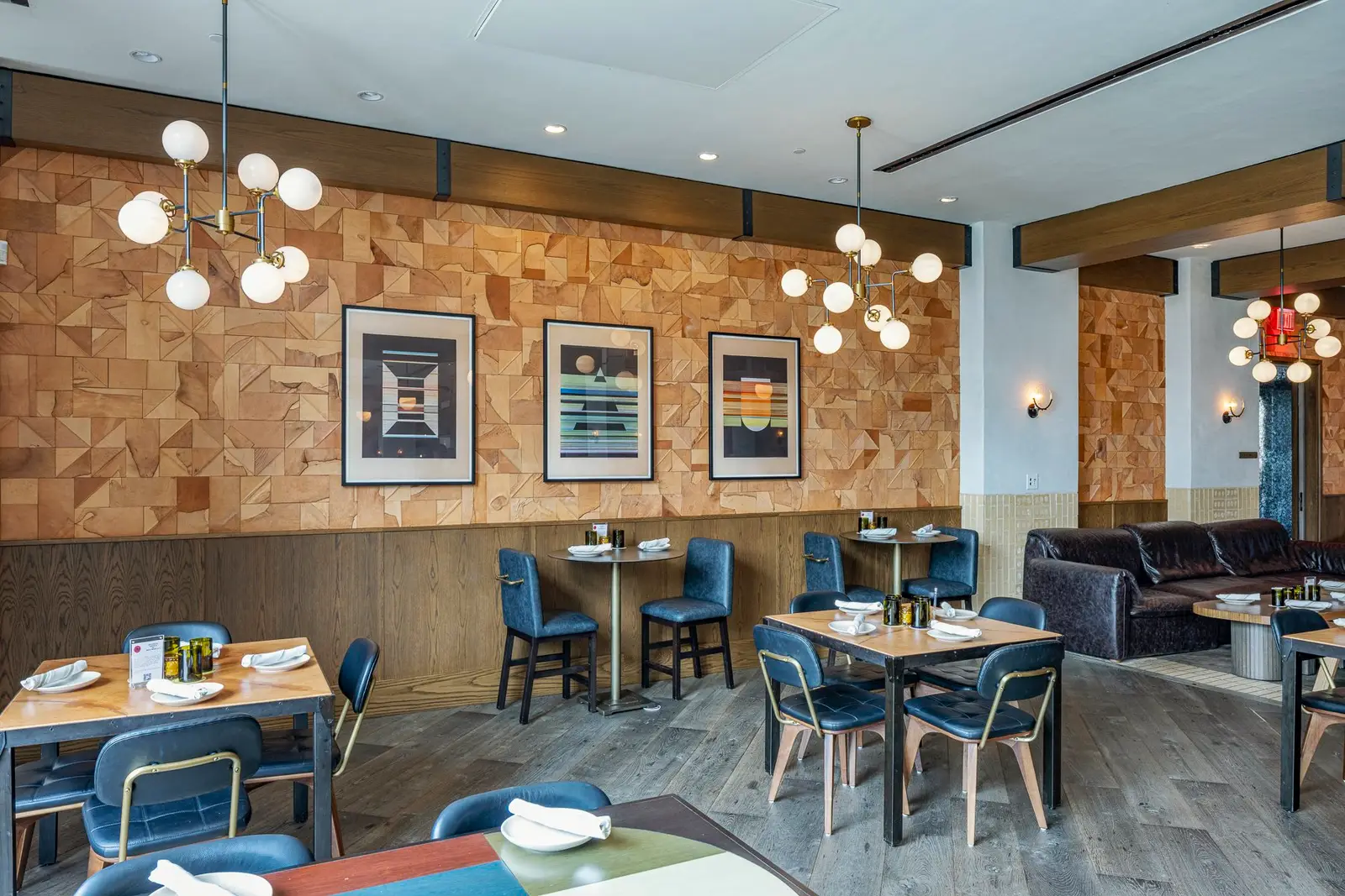 Thompson Hotel dining room with a wood block wall, blue chairs and globe lights