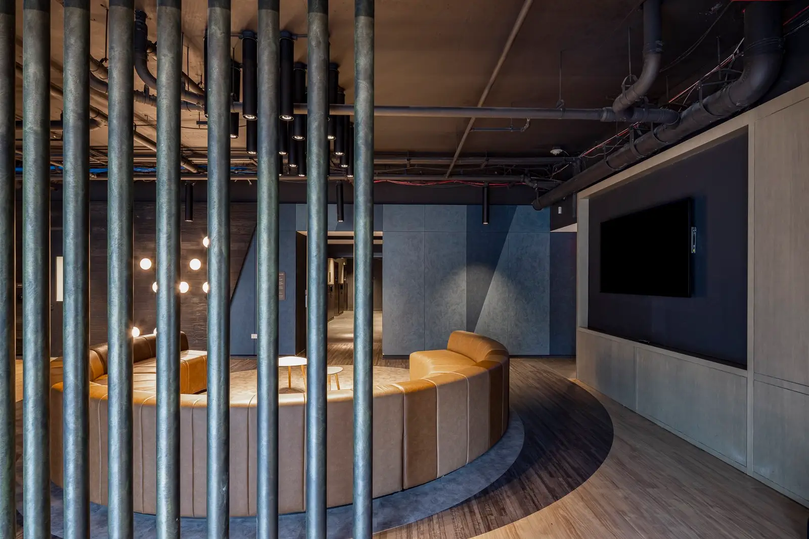 Thompson Hotel curved banquette lounge behind a vertical pipe screen