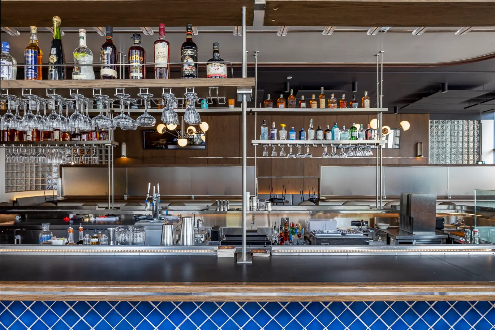 Thompson Hotel bar with hanging glass racks and a blue tile front