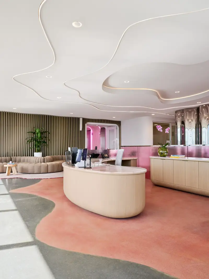TikTok reception with a curved wood-front desk, wavy ceiling and pink floor