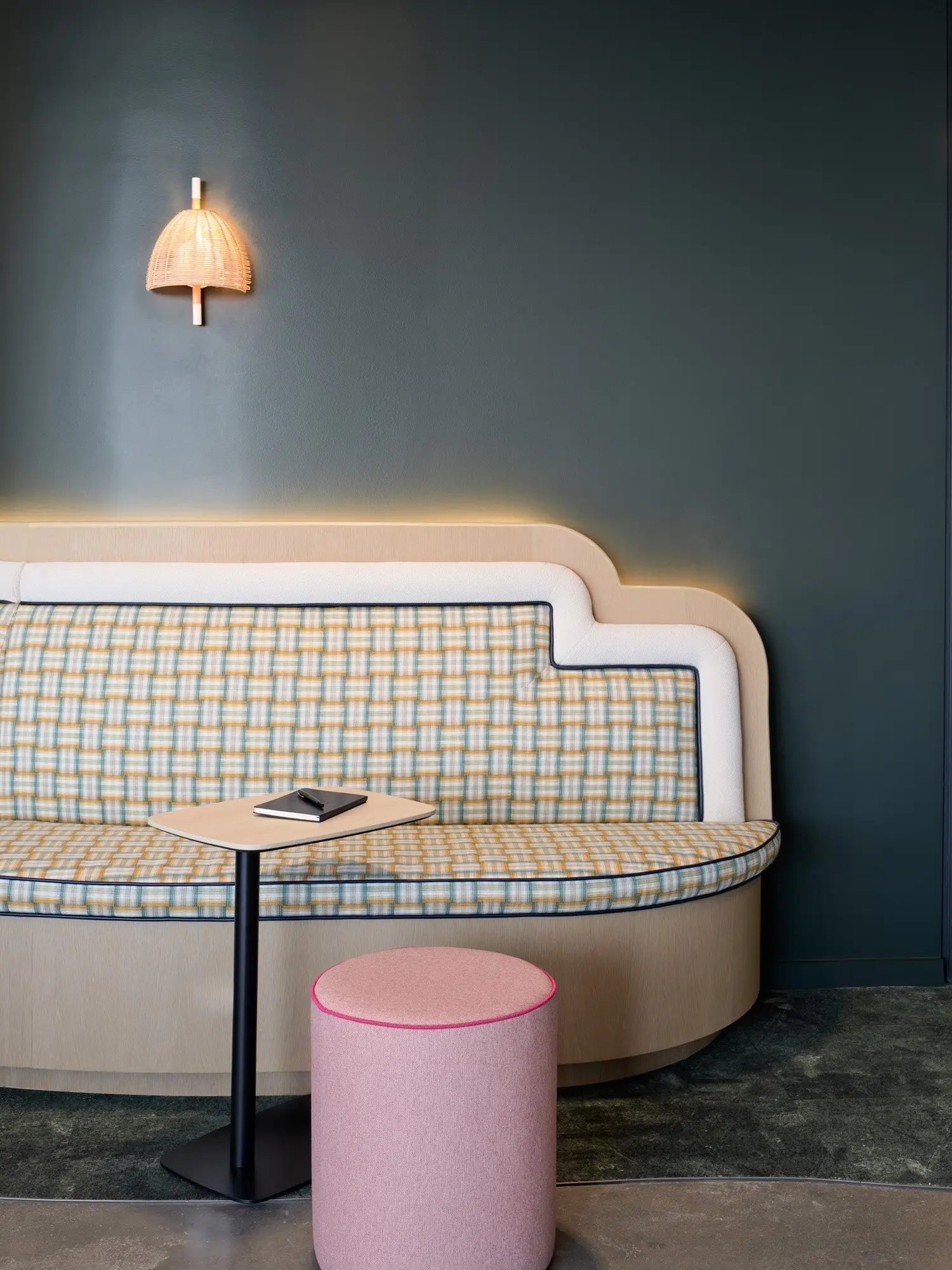 TikTok checked upholstered banquette under a wall sconce on a dark blue wall