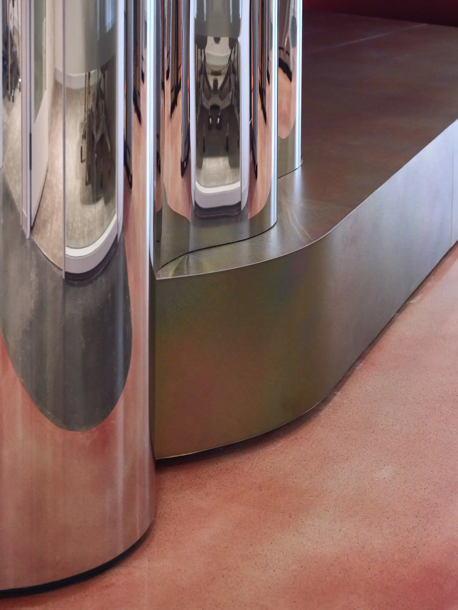 TikTok curved polished metal column and metal-clad curved base on a pink floor