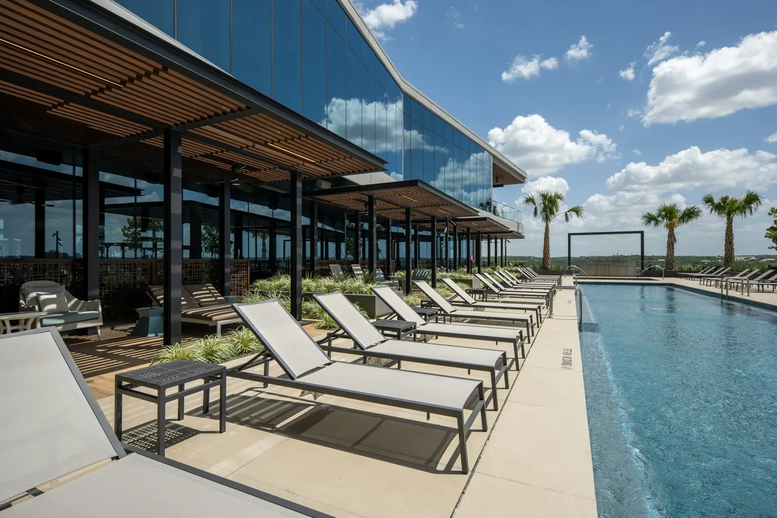 Travis Tower rooftop pool deck with lounge chairs under a wood slat shade structure