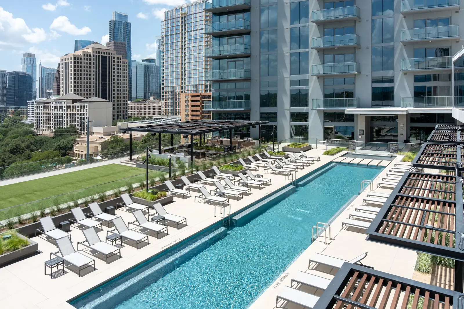 Travis Tower rooftop pool and lounge deck beside a high-rise with a wood slat pergola