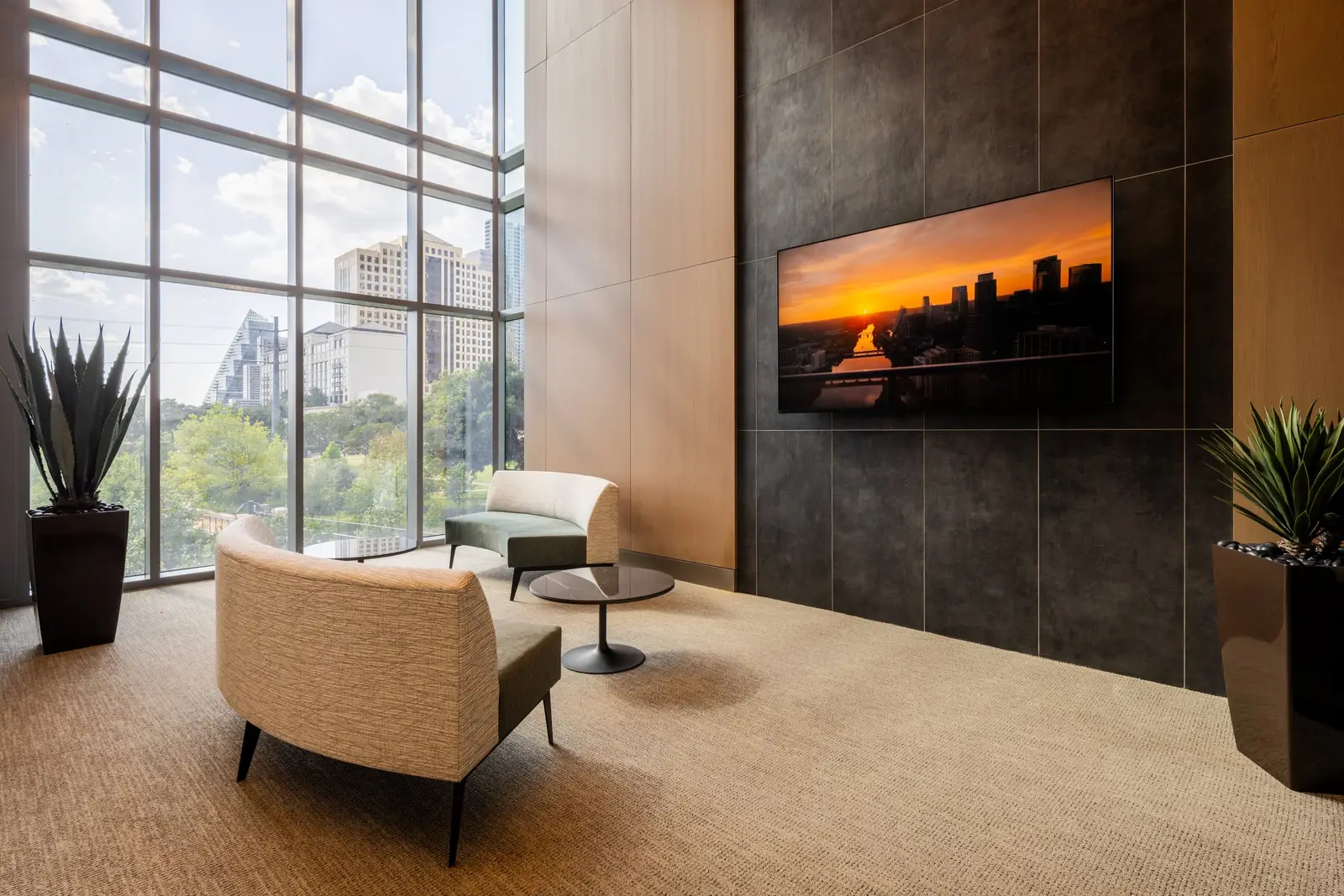 Travis Tower lounge with a wood paneled wall, dark tile TV wall and curved chairs