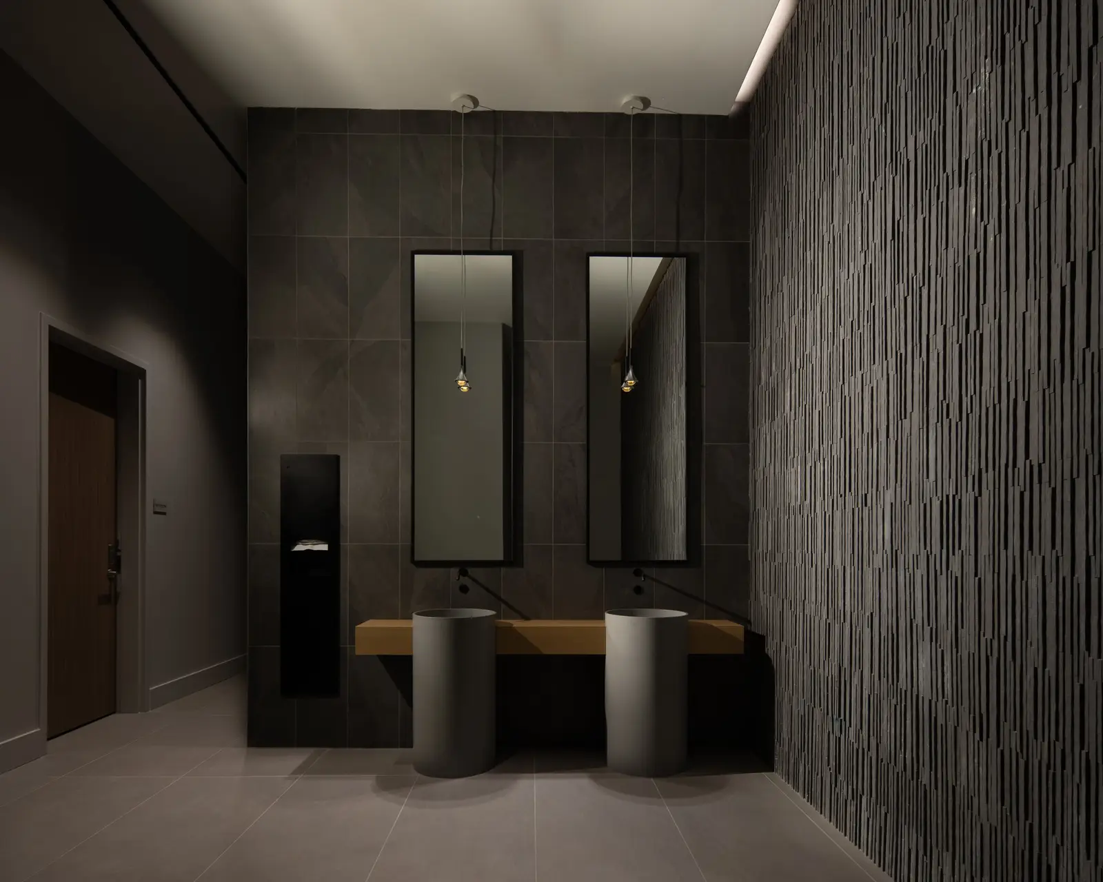 Travis Tower restroom with dark tile walls, pedestal sinks and tall mirrors