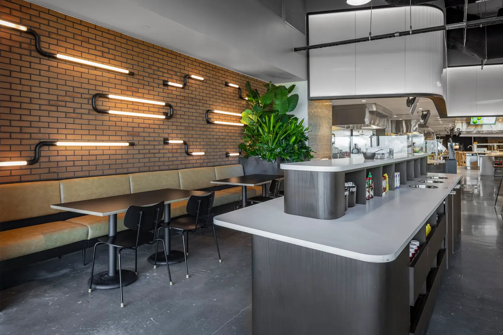 Undisclosed Project dining area with a brick wall, light-strip fixtures and a curved counter
