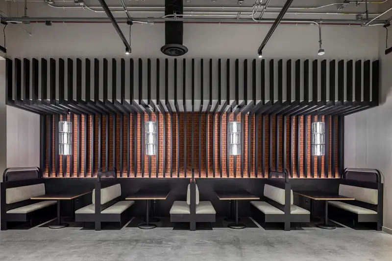 Undisclosed Project booth seating below a black slat ceiling feature and wood slat wall