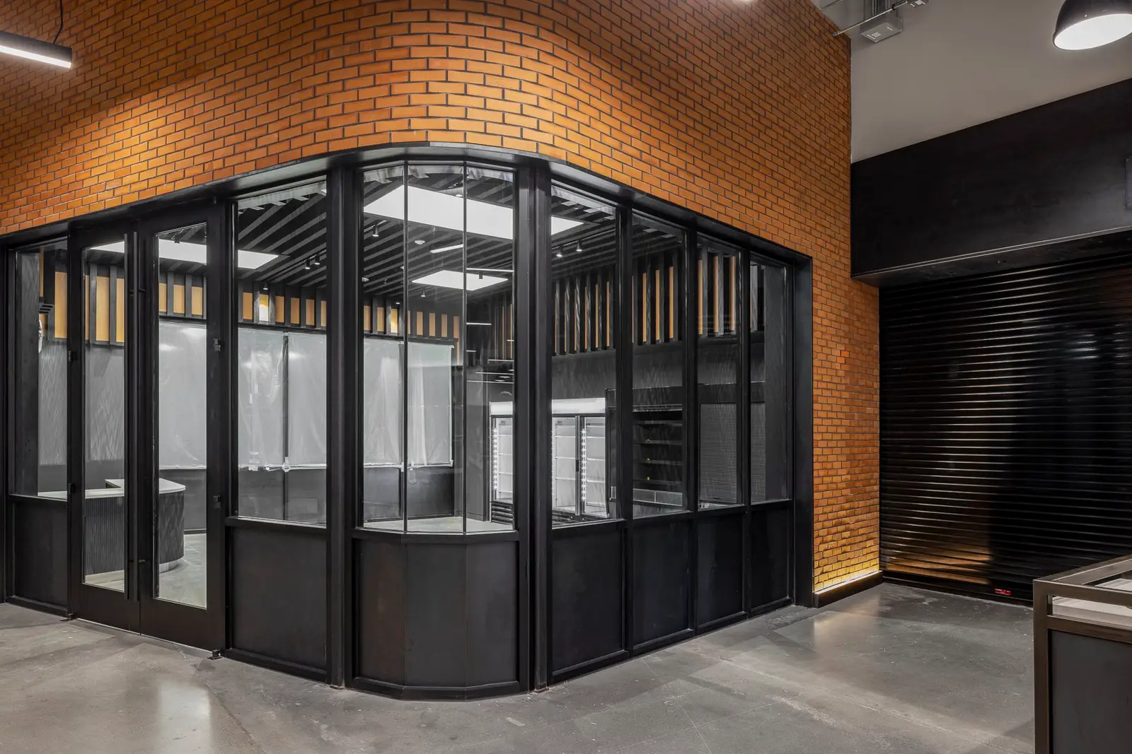 Undisclosed Project glass and black metal enclosure at a brick wall corner
