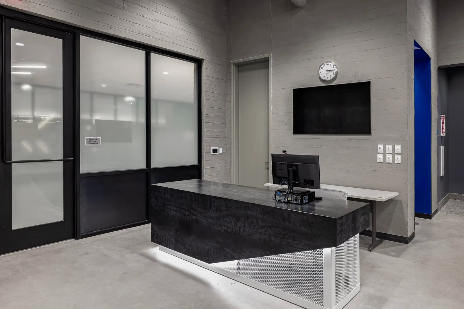 Undisclosed Project reception desk with a dark top in front of a glass-fronted wall