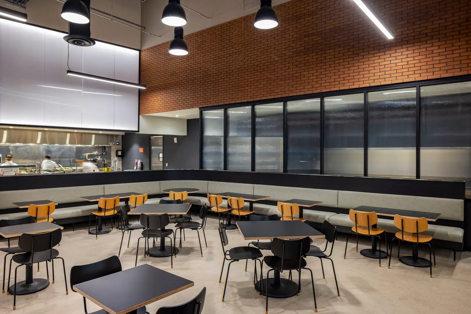 Undisclosed Project dining area with booths, a brick accent wall and black-framed windows