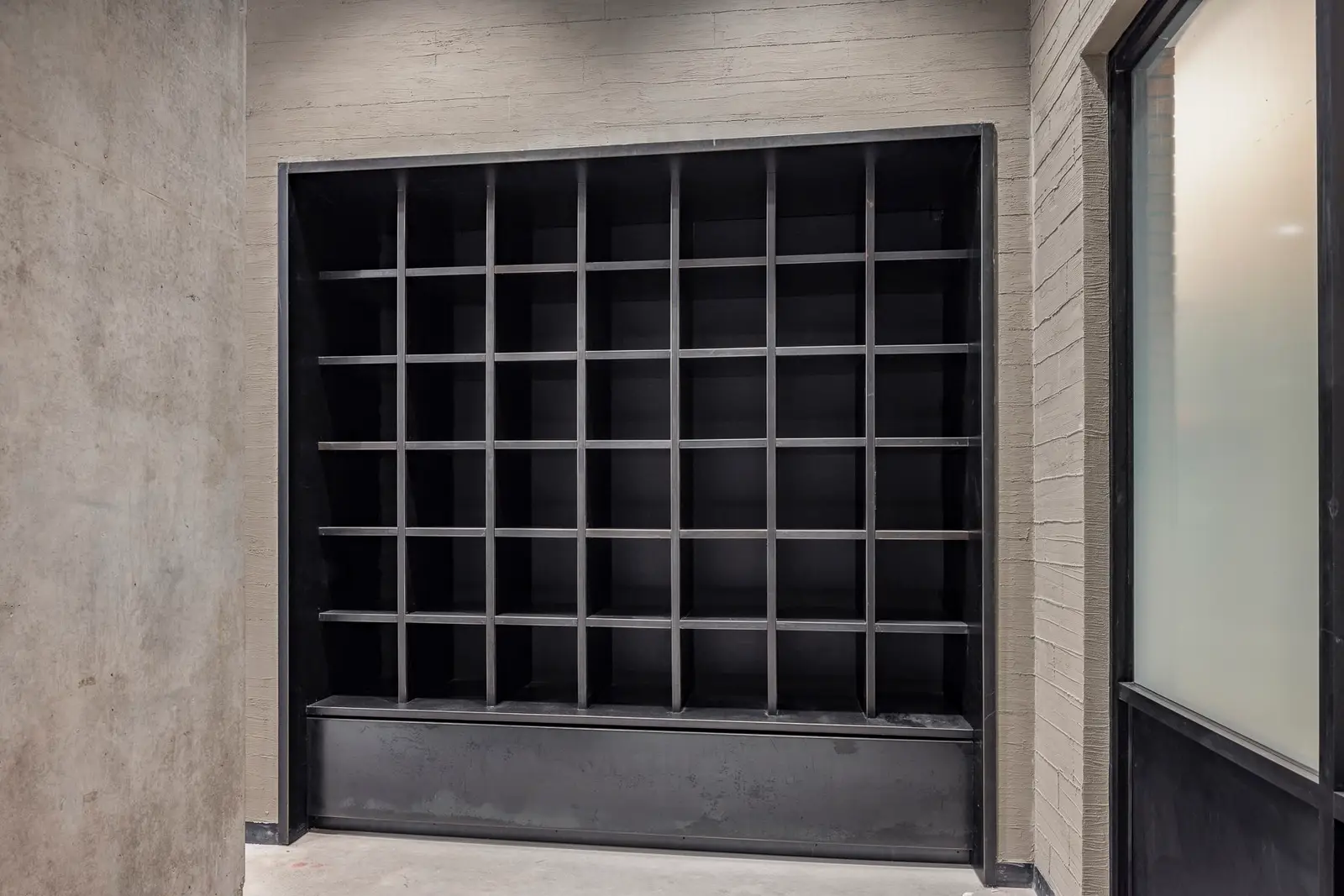 Undisclosed Project black cubby shelving wall in a gray corridor
