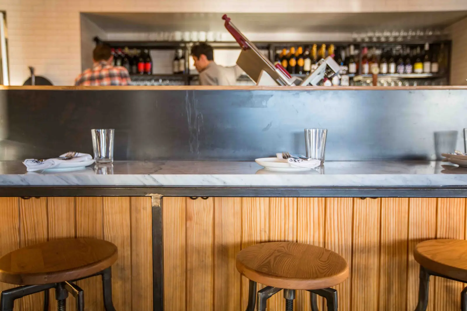 Unit-D Pizzaria open kitchen pass with a stainless counter and wood stools