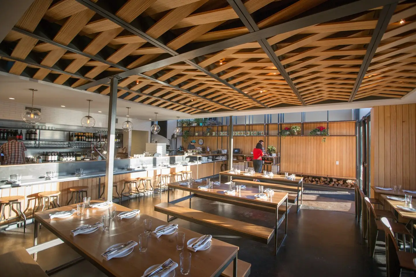 Unit-D Pizzaria dining room with a woven wood and steel ceiling and long tables